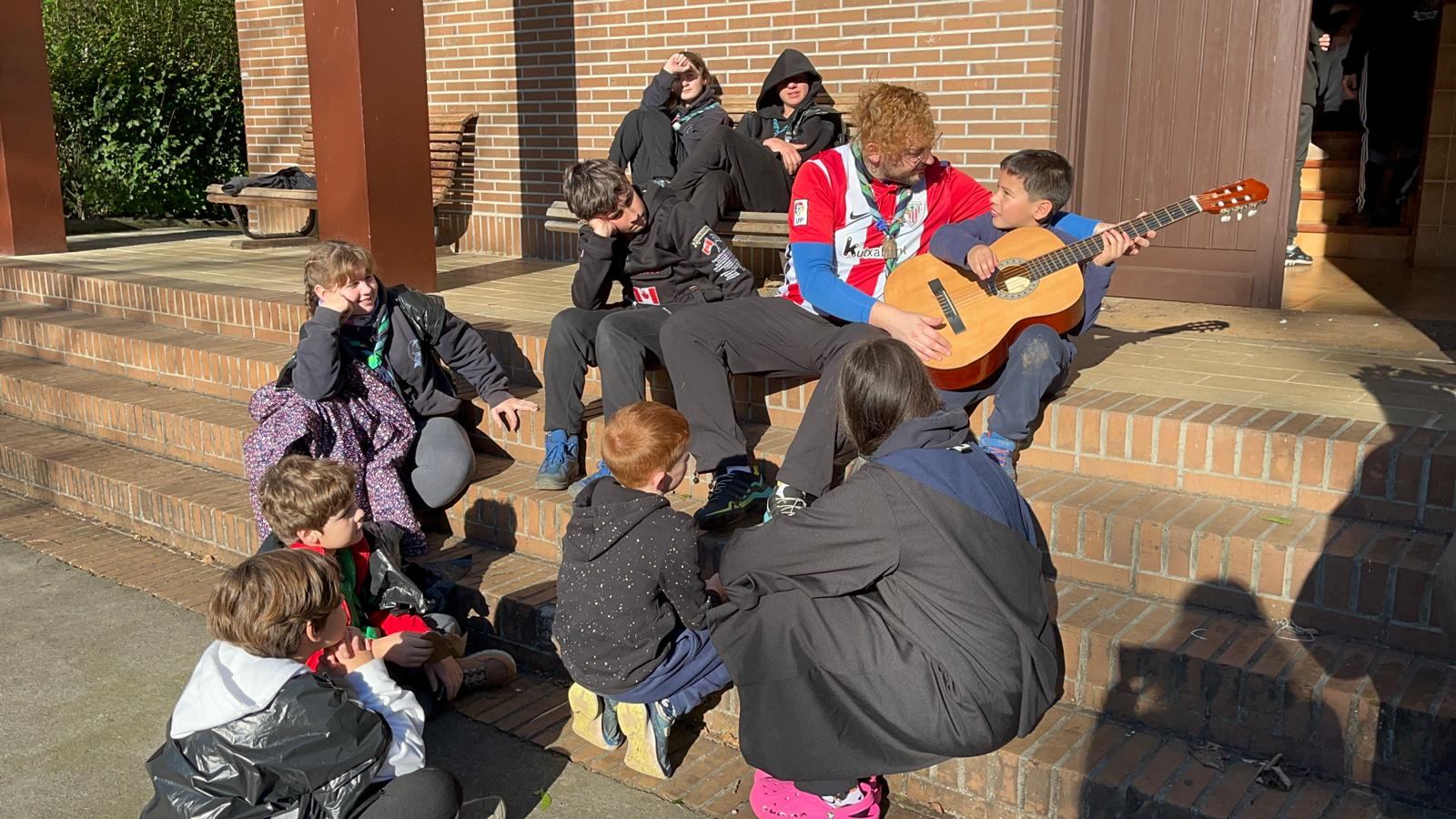 Un monitor toca la guitarra con los más pequeños en las escaleras del local