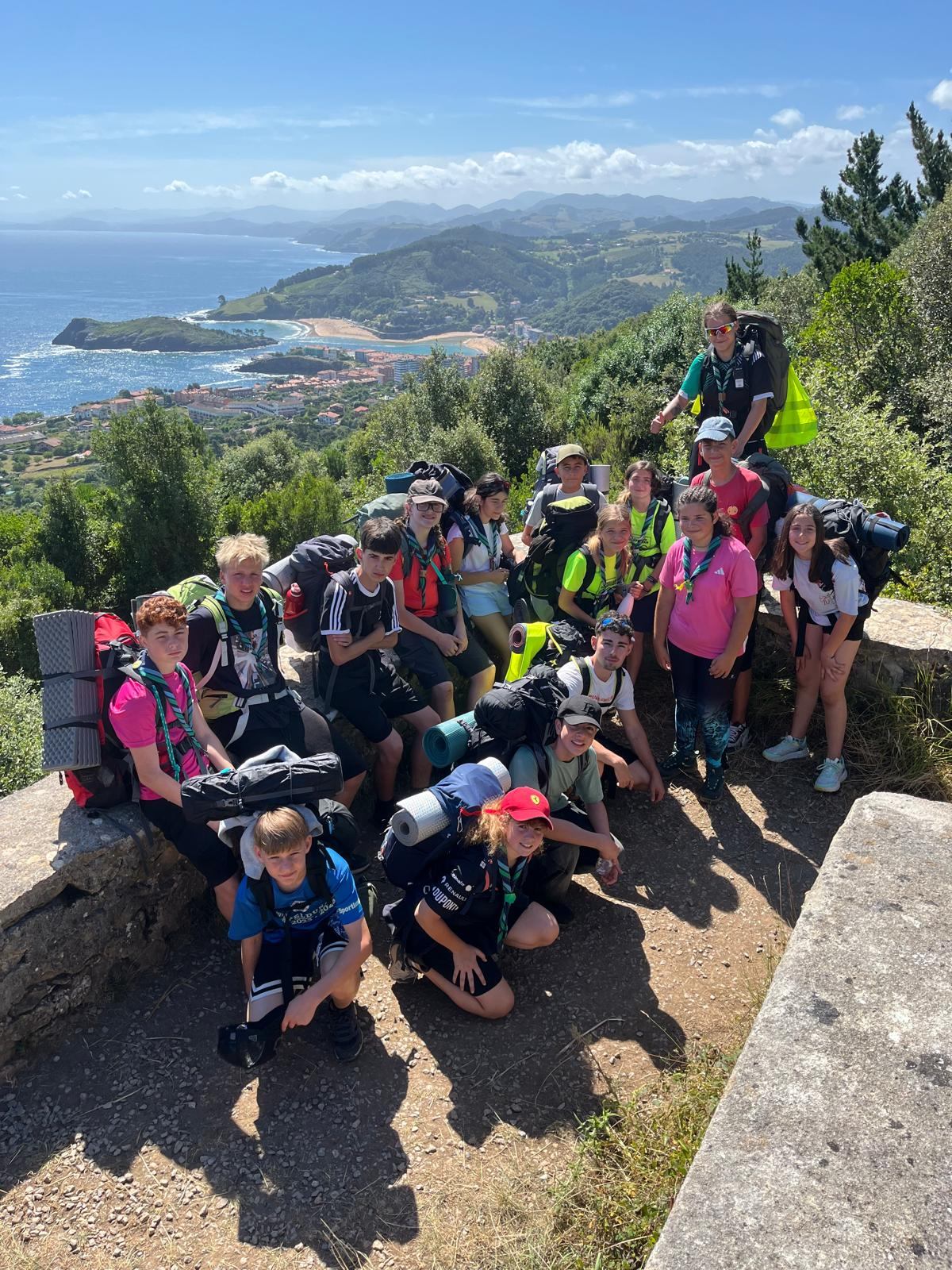 Chavales con mochilas y pañoletas en un mirador sobre la costa