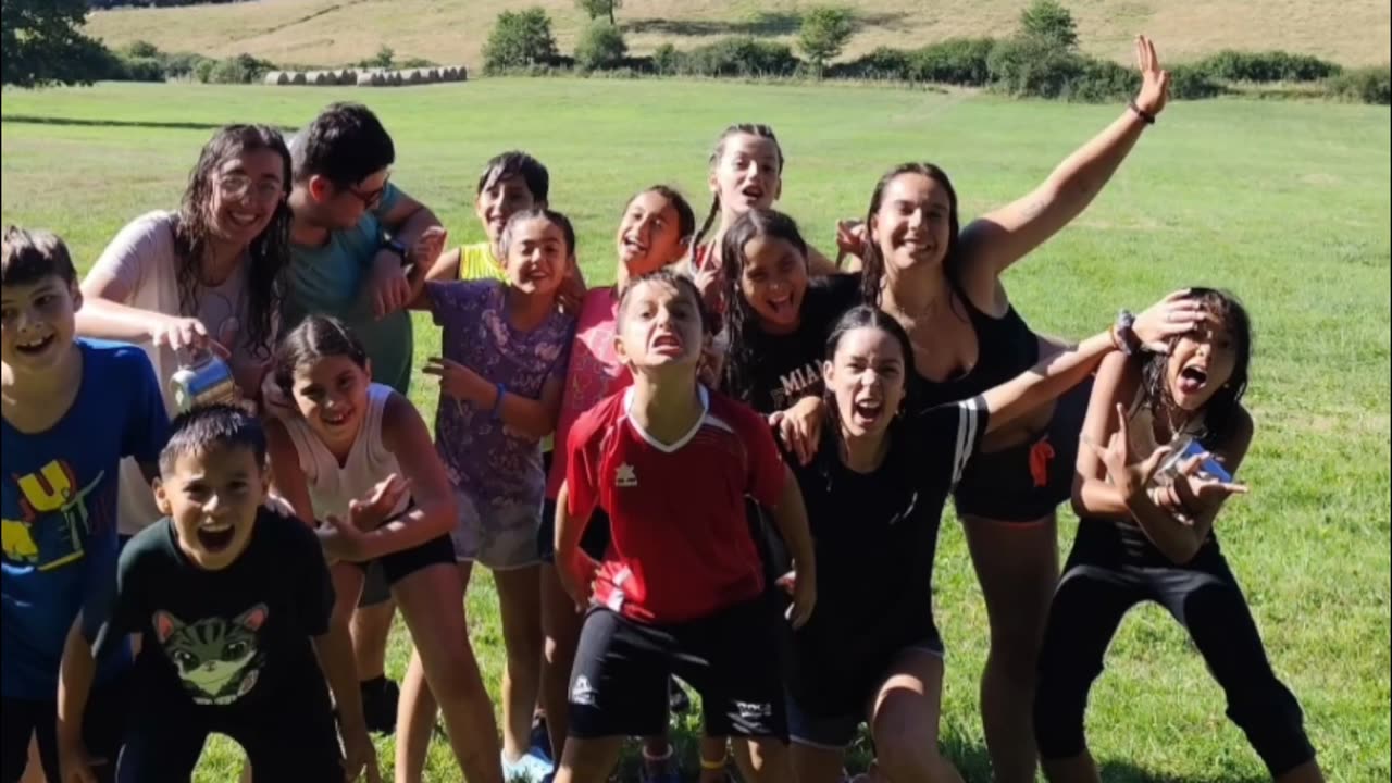 Chavales saltando y riendo en una campa durante el campamento de verano 2025